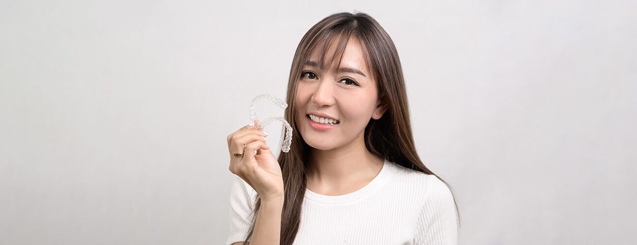 Girl holding Invisalign in her hand and smile