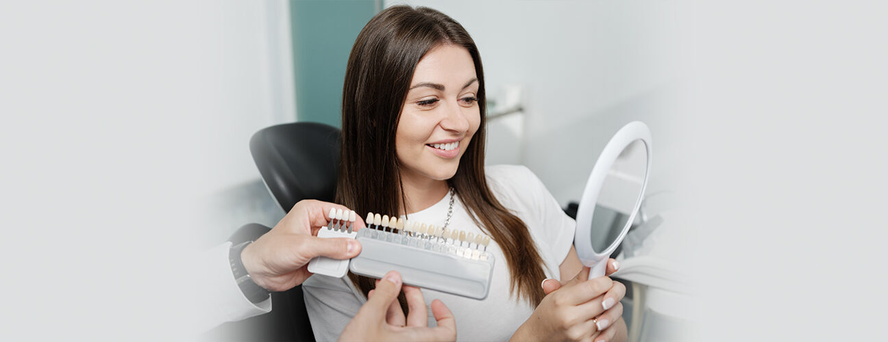 Girl is taking dental veneers treatment and looking into mirror and smile