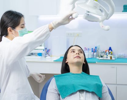 dentist is setting up to examine girl and girl is laying on dental chair